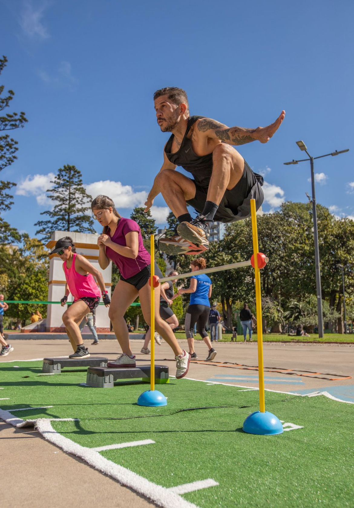 Clase de alta intensidad saltando vallas sobre césped sintético en el parque